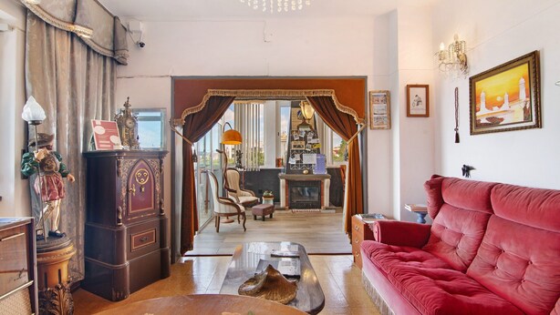 A living room with a red sofa, a wooden coffee table, a vintage clock, and a chandelier. - Room 'Duplo Superior' with Balcony, Wi-Fi and Air Conditioning (São Brás de Alportel)