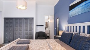 A bedroom with a bed, pillows, a chair, a desk, and a door. - Room 'Duplo Superior' with Balcony, Wi-Fi and Air Conditioning (São Brás de Alportel)