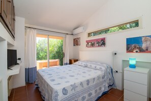 A bedroom with a bed, a desk, a chair, a window, and a wall-mounted air conditioner. - Villa 'Viola Con Piscina E Giardino' with Sea View, Private Pool and Wi-Fi (Punta Sardegna)