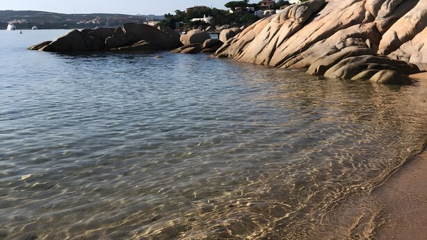 A coastal landscape with clear water, rocky formations, and distant buildings. - Villa 'Viola Con Piscina E Giardino' with Sea View, Private Pool and Wi-Fi (Punta Sardegna)