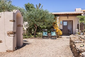 A building with a stone facade, a wooden door, and a small patio area with two chairs. - Cottage 'Mussenya 1' with Balcony, Wi-Fi and Air Conditioning (Illes Balears)