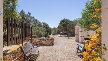 A gravel courtyard with a wooden fence, a stone wall, and a bench.