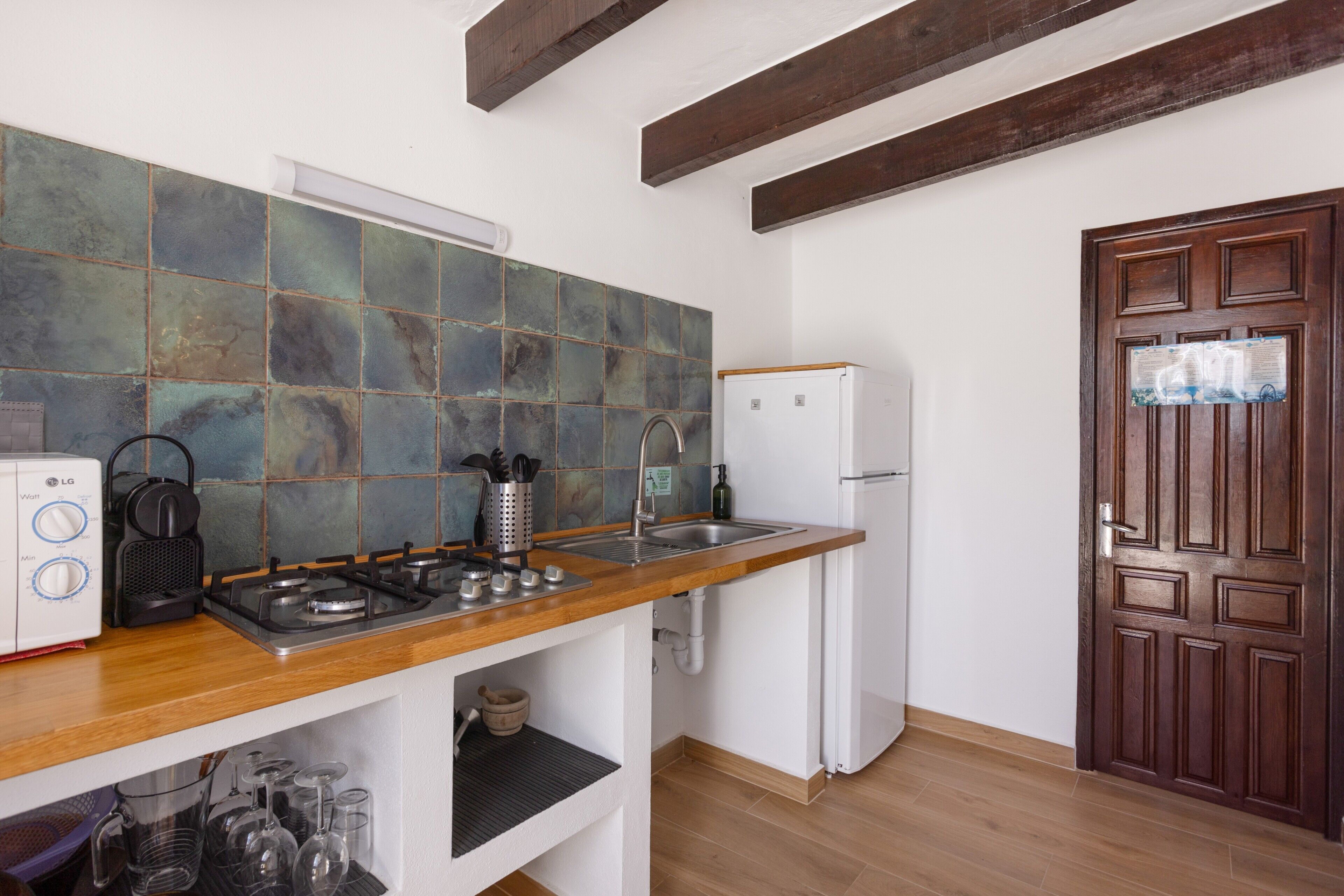 A kitchen with a wooden countertop, a white refrigerator, and a tiled backsplash.
