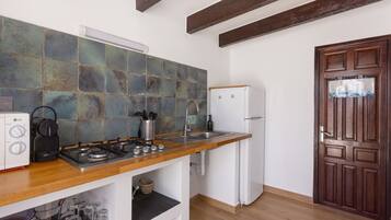 A kitchen with a wooden countertop, a white refrigerator, and a tiled backsplash.