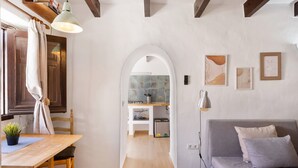 Une pièce comprenant une table à manger en bois, un canapé gris, un lampadaire et un mur recouvert de carreaux.