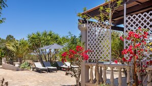 Une terrasse avec des chaises longues, une pergola et une clôture en treillis blanche.
