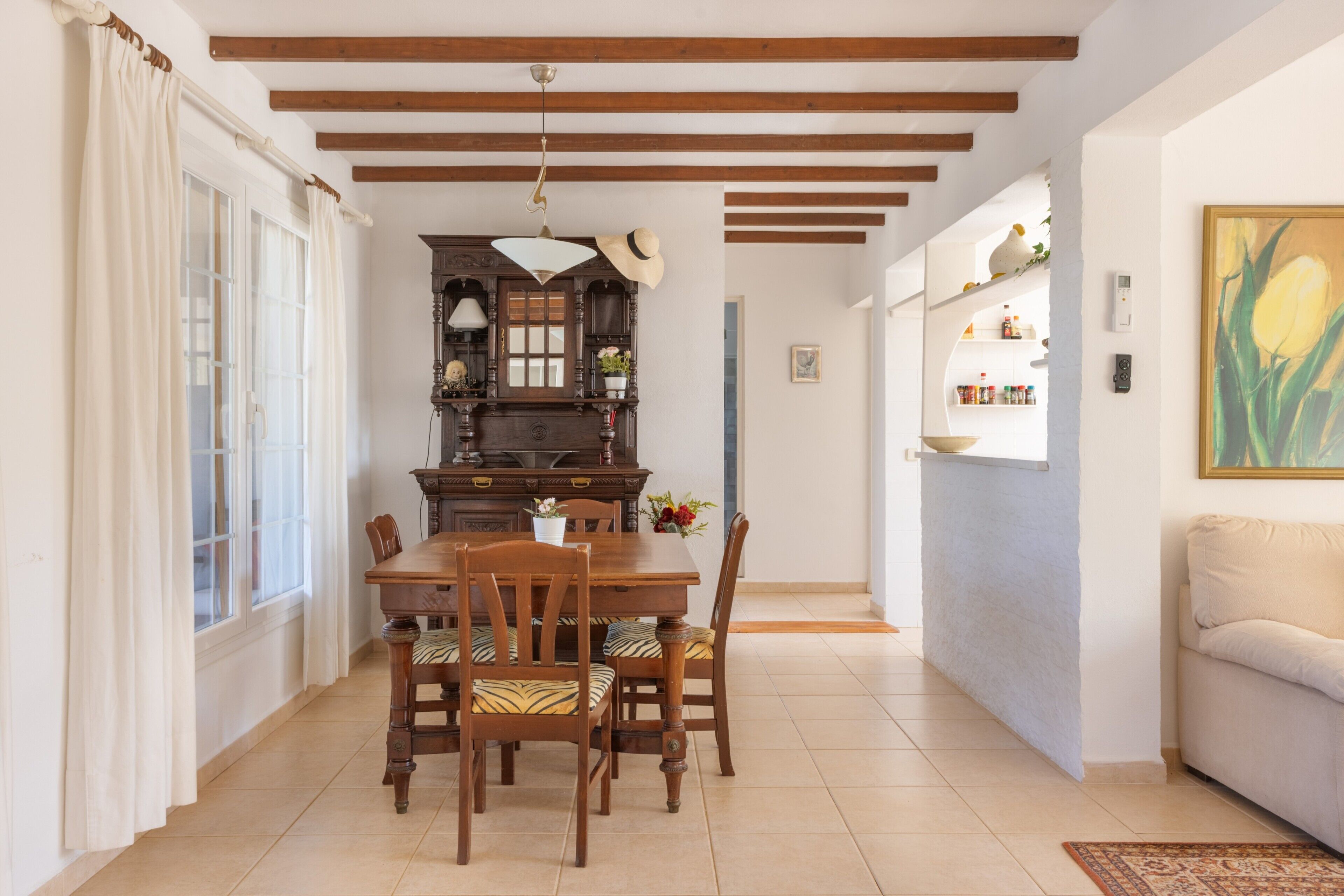 A dining area with a wooden table and chairs, a chandelier, and a view of the living room.