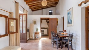 Un espace repas comprenant une table et des chaises en bois, un banc et un ventilateur de plafond.