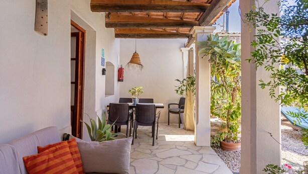 Un espace patio aménagé avec un canapé, des fauteuils, une table et des plantes en pot.