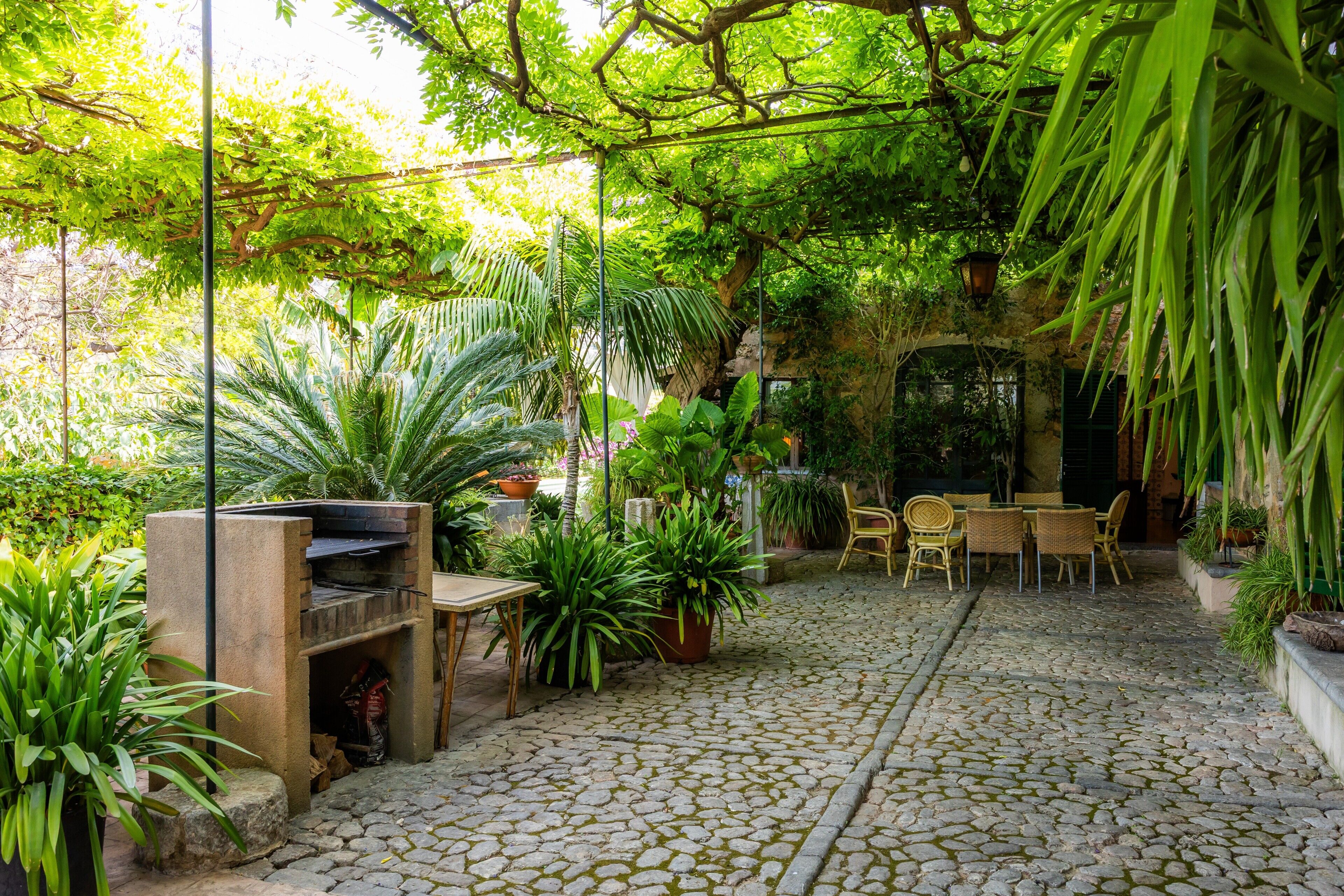 Eine Terrasse im Freien mit Steinböden, Pflanzkübeln und Gartenmöbeln.