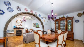 Un comedor con una gran mesa de madera, sillas y una araña.