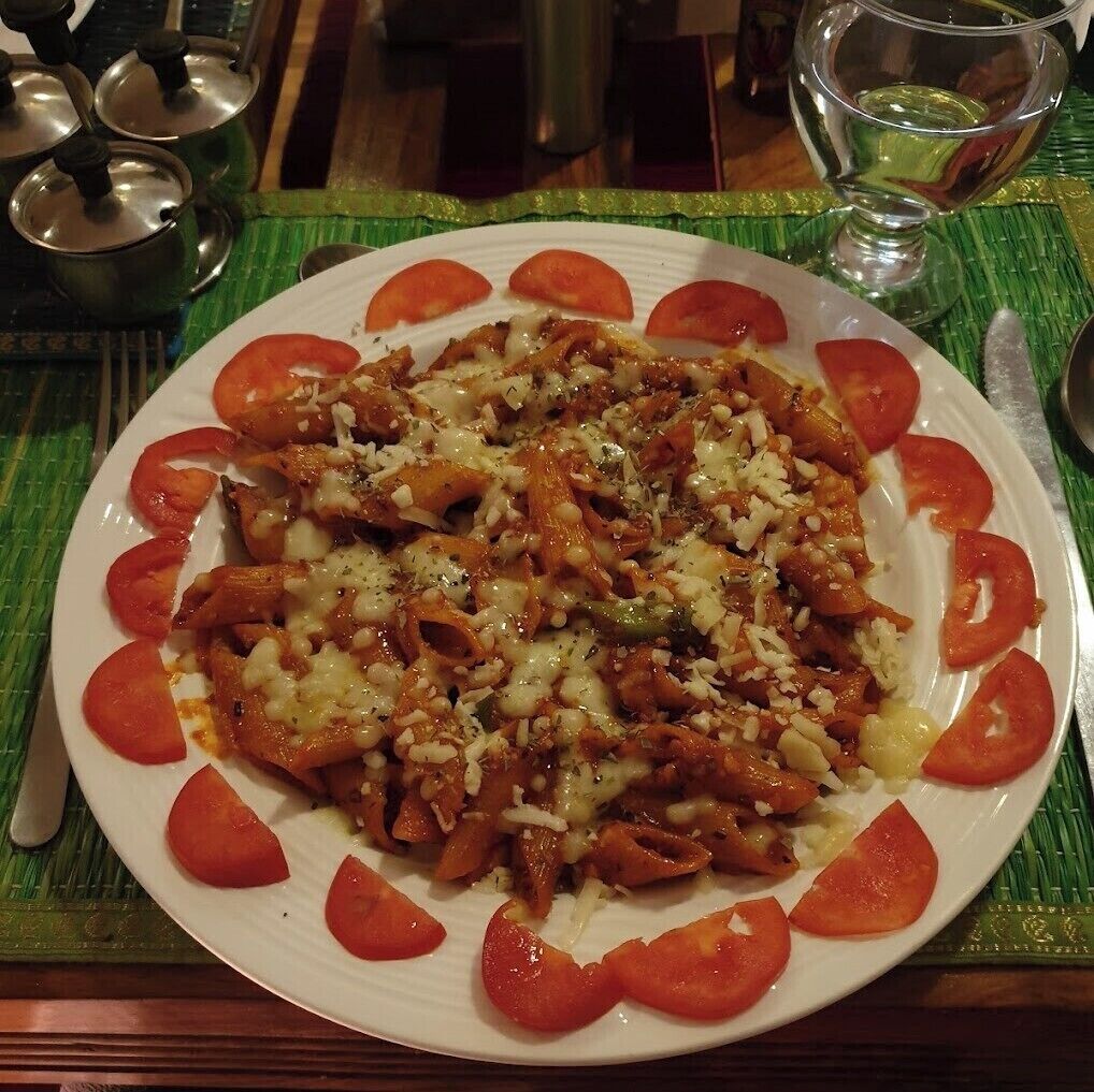 Eine Pasta-Käse-Tomaten-Kombination auf einem Tisch mit grüner Tischmatte.