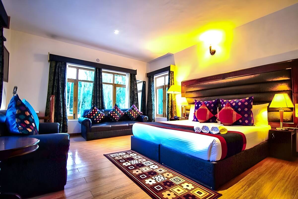 Ein Hotelzimmer mit einem großen Bett, einer Couch, einem kleinen Tisch und einem Fenster mit Vorhängen.