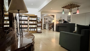 A spacious living area with a large bookshelf, a reception desk, and a modern sofa. - Gomang Boutique Hotel  (Leh)