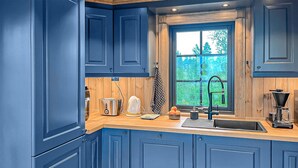 A kitchen with blue cabinets, a wooden countertop, a window with a view of trees, a sink, and a coffee maker. - 2 bedroom awesome home in Engerdal (Engerdal)