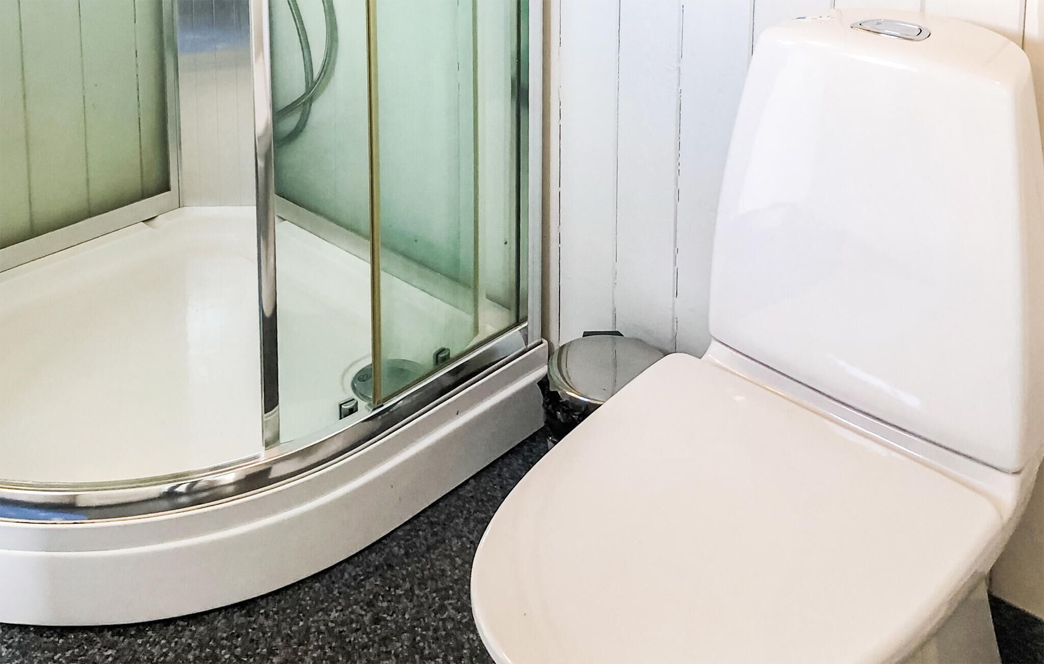Une petite salle de bain d’angle avec une douche et des toilettes.