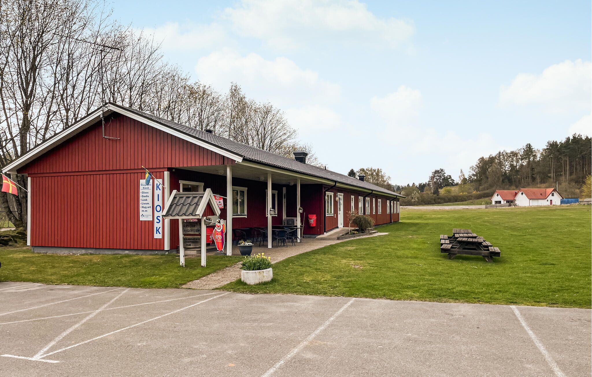 Un bâtiment rouge doté d’un porche abrité, d’un panneau indiquant les équipements disponibles et d’un espace de stationnement.