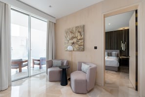 A modern hotel room with a large window, a sofa, a small table, and a bed.