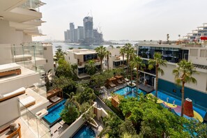 Un área de piscina en la azotea con varias piscinas, palmeras y vistas del horizonte de la ciudad.