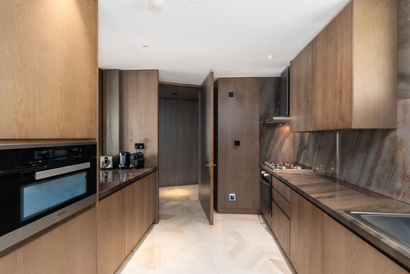 A modern kitchen with wooden cabinetry, a built-in oven, and a marble backsplash.