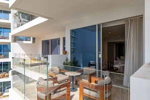 A modern apartment with a glass balcony, furnished with sofas and a round table.