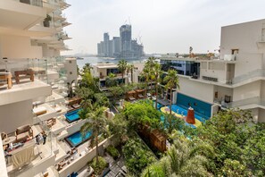 A rooftop pool area with multiple levels of outdoor seating and a view of a city skyline in the background.