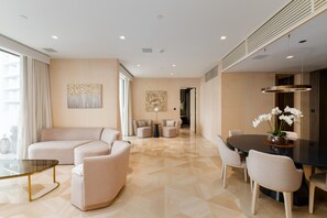 A modern living room with a sofa, chairs, a dining table, and artwork on the walls.