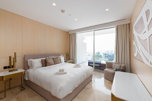 A modern hotel room with a large bed, a desk, and a balcony with a view.