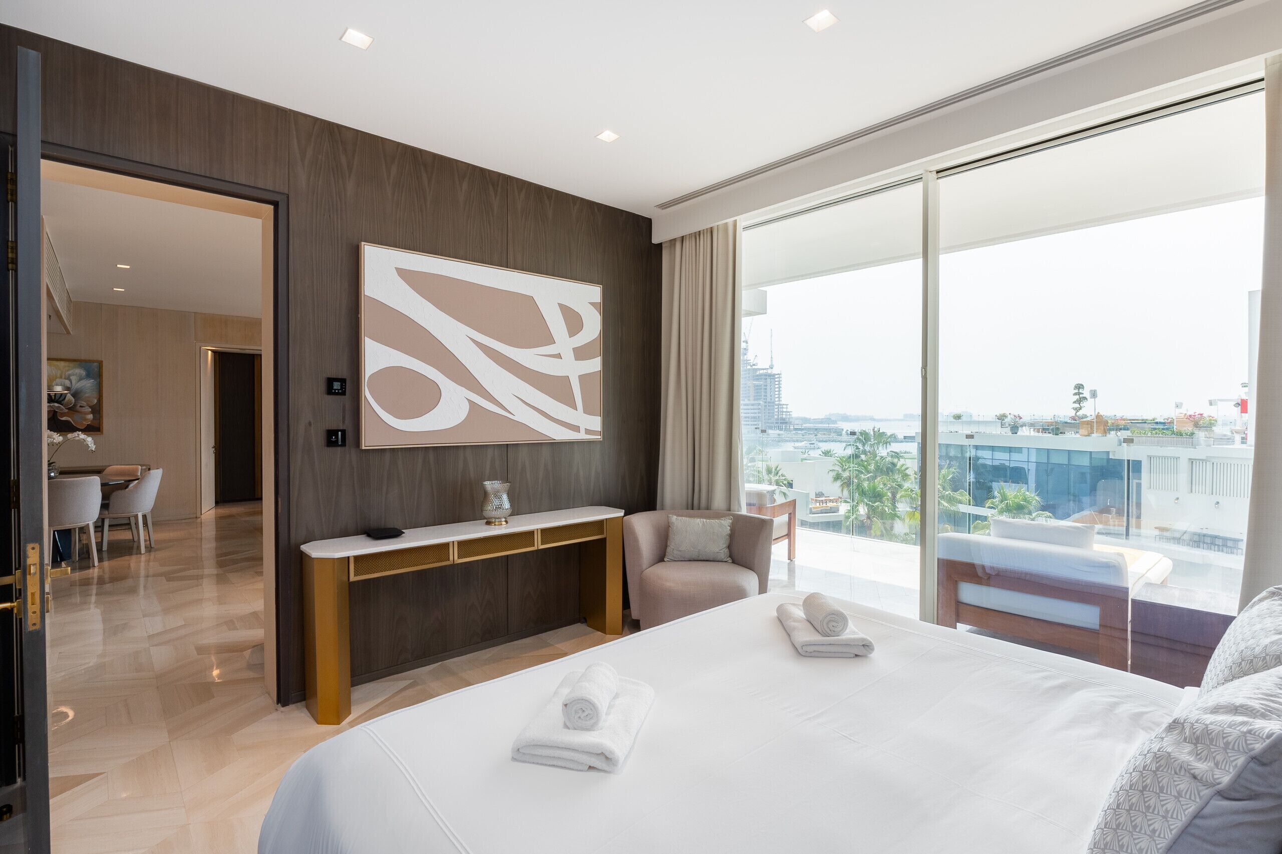Une chambre d’hôtel moderne dotée d’un grand lit, d’un bureau, d’une chaise et d’une grande fenêtre donnant sur la ville.