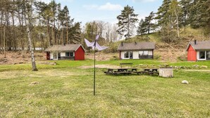 Ländliche Szenerie mit drei Ferienhäusern, einem Picknicktisch und einer Fahnenmast.