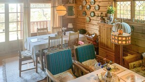 A cozy cabin interior with a dining area, wooden walls, and a large window.