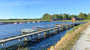 Een rustig water met afgemeerde boten, een houten steiger en rode gebouwen op de achtergrond.