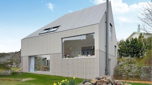 A modern house with a sloped roof, large windows, and a wooden deck. - Stunning home in Brännö (Brännö)