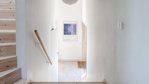 A hallway with a wooden staircase, a hanging light fixture, and a framed artwork on the wall. - Stunning home in Brännö (Brännö)