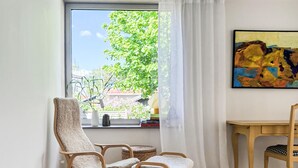 A room with a large window, a painting on the wall, and a chair with a cushion. - Stunning home in Brännö (Brännö)