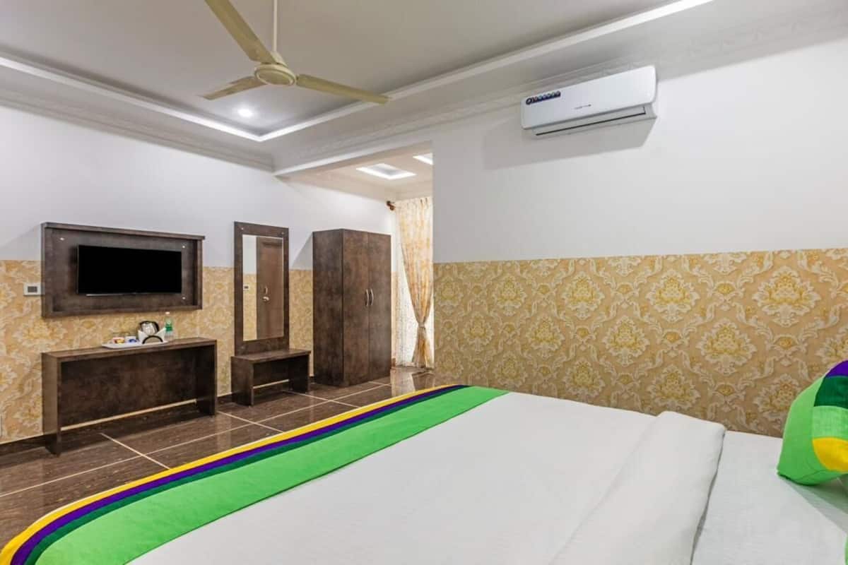 Een hotelkamer met een bed, een televisie, een kledingkast en een airconditioner.