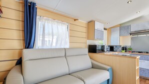 A modern RV interior with a sofa, kitchenette, and wooden panel walls. - Super Octalia (camping 5*) by Interhome (Les Pieux)