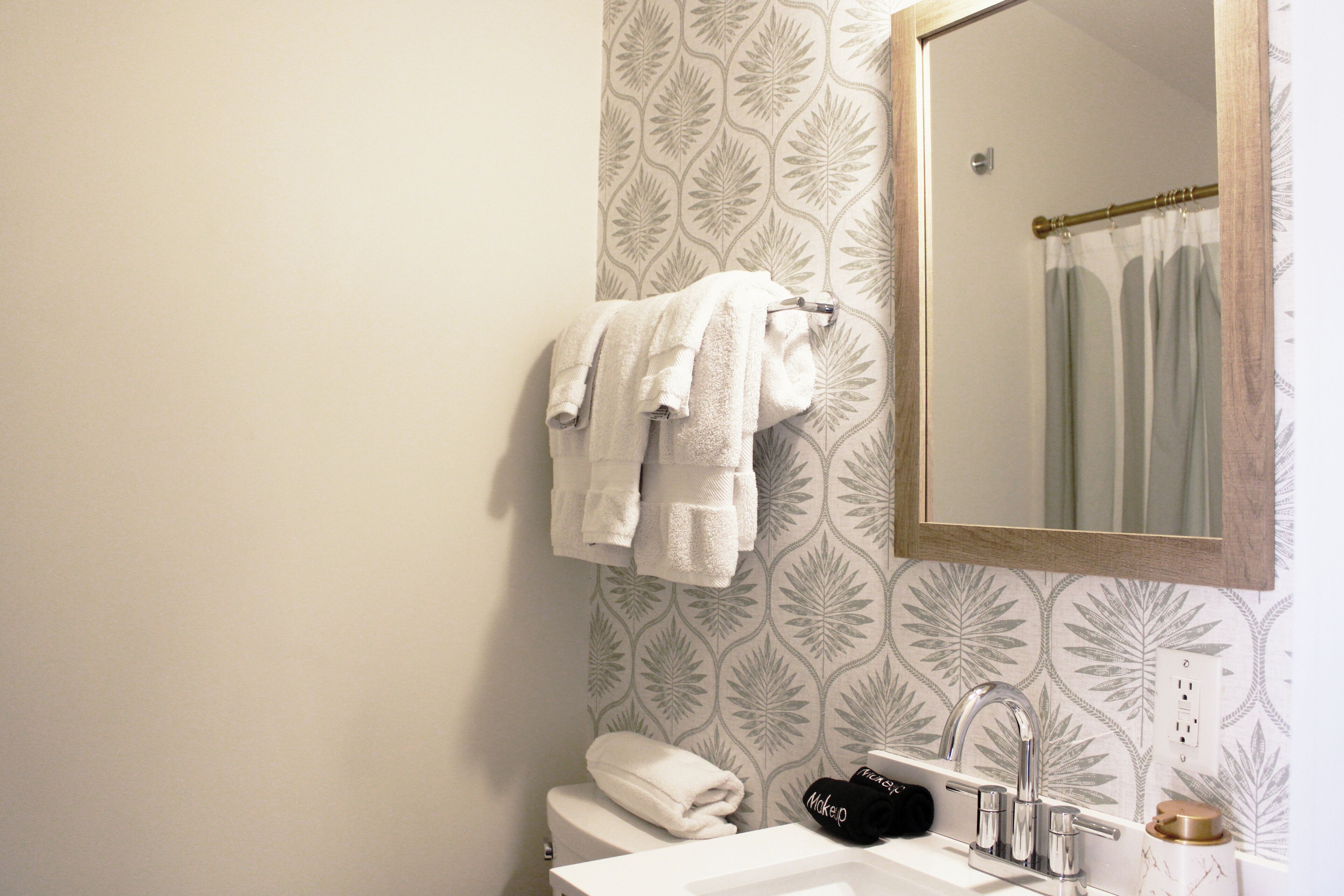 A bathroom with a white sink, a mirror, and a towel rack with towels.