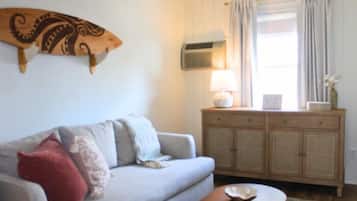 Un salon comprenant un canapé, un meuble en bois, une lampe et un élément décoratif mural.