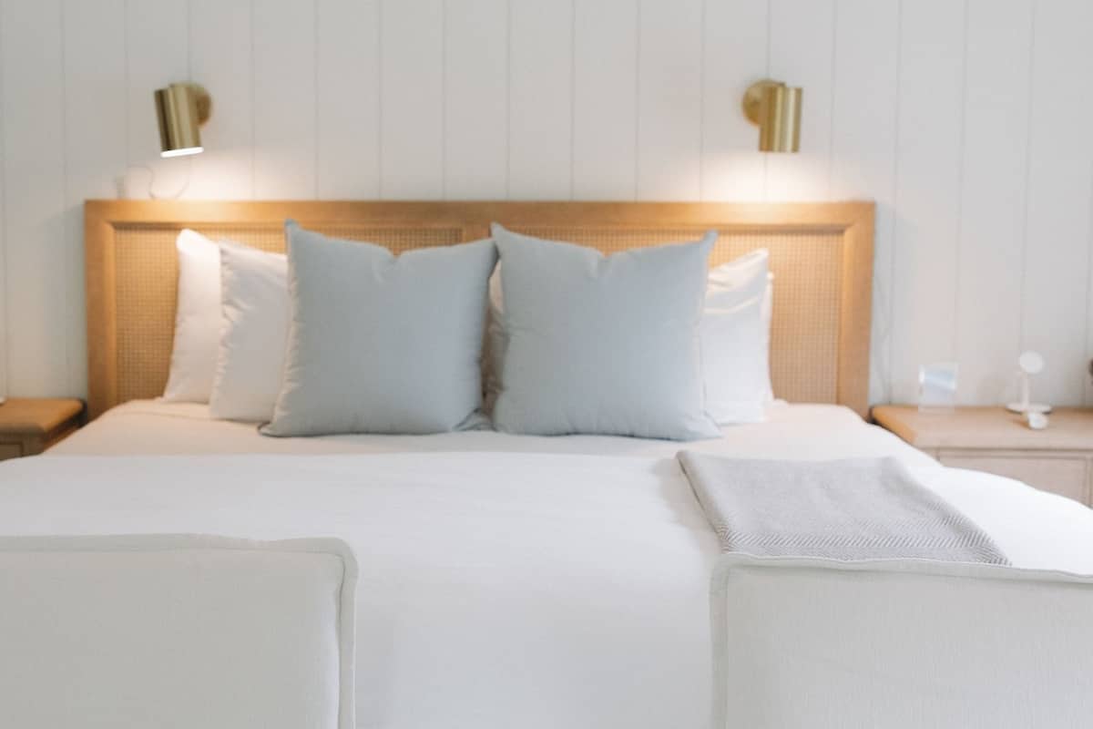 A hotel room with a large bed, two bedside tables, and a headboard with wall-mounted lamps.