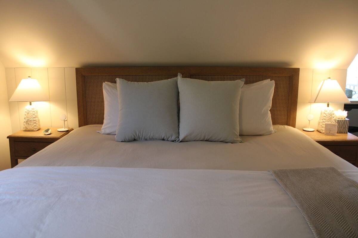 A neatly made bed with two pillows, a wooden headboard, and bedside lamps on either side.