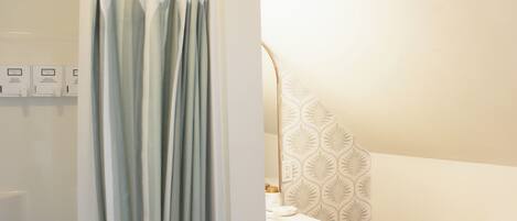 Ein Badezimmer mit Duschvorhang, Toilette, Waschbecken mit Spiegel und einer Wand mit Muster.