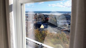 A view from a window overlooking a coastal town with buildings, a road, and the ocean. - The Trident Inn (Ogunquit)