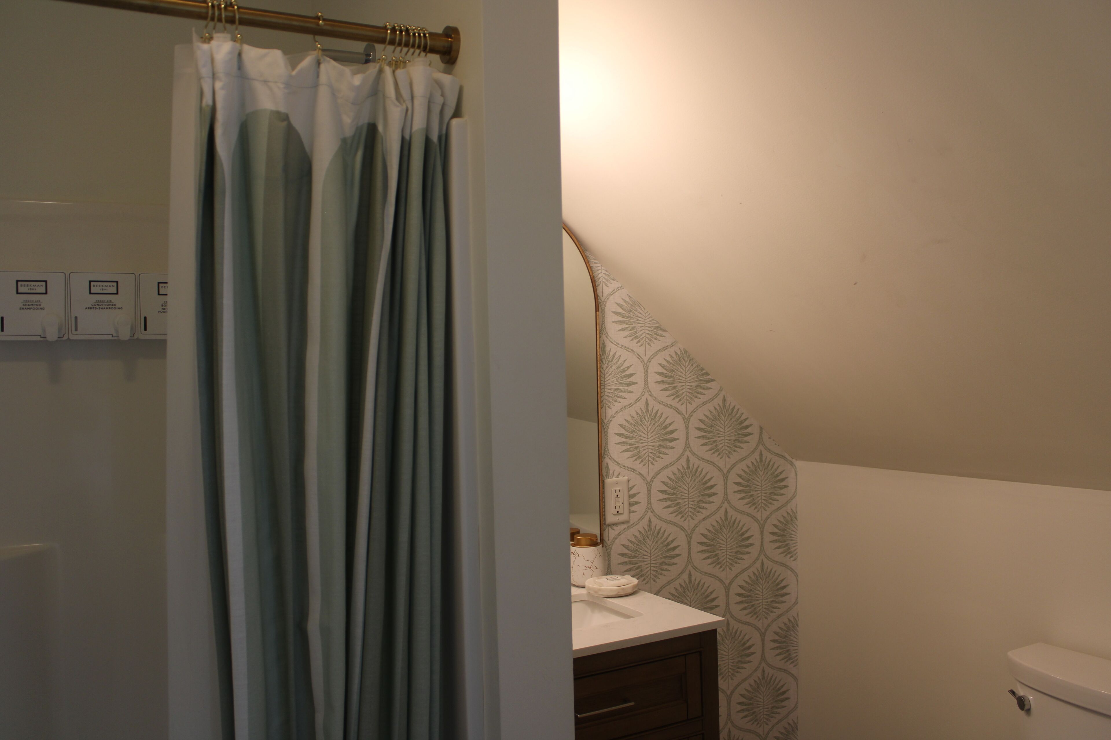 A bathroom with a shower curtain, a toilet, a sink with a towel, and a patterned wall.