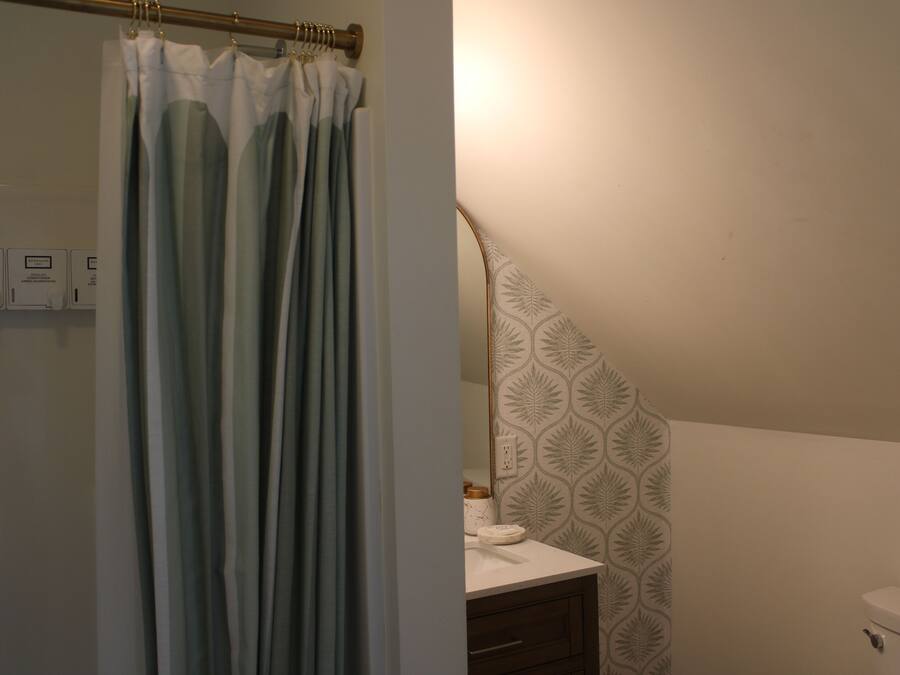A bathroom with a shower curtain, a toilet, a sink with a towel, and a patterned wall.