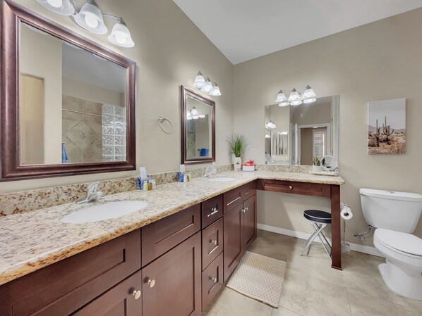 A modern bathroom with two sinks, a large mirror, and a toilet.