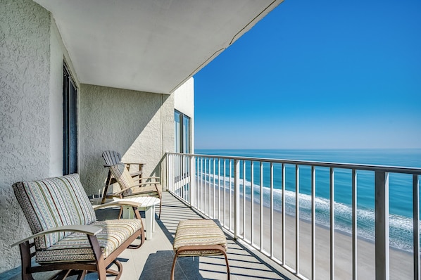A balcony with a view of the ocean, furnished with chairs and a bench. - One Ocean Place 1209 - Garden City Luxury Oceanfront Condo (Garden City Beach)