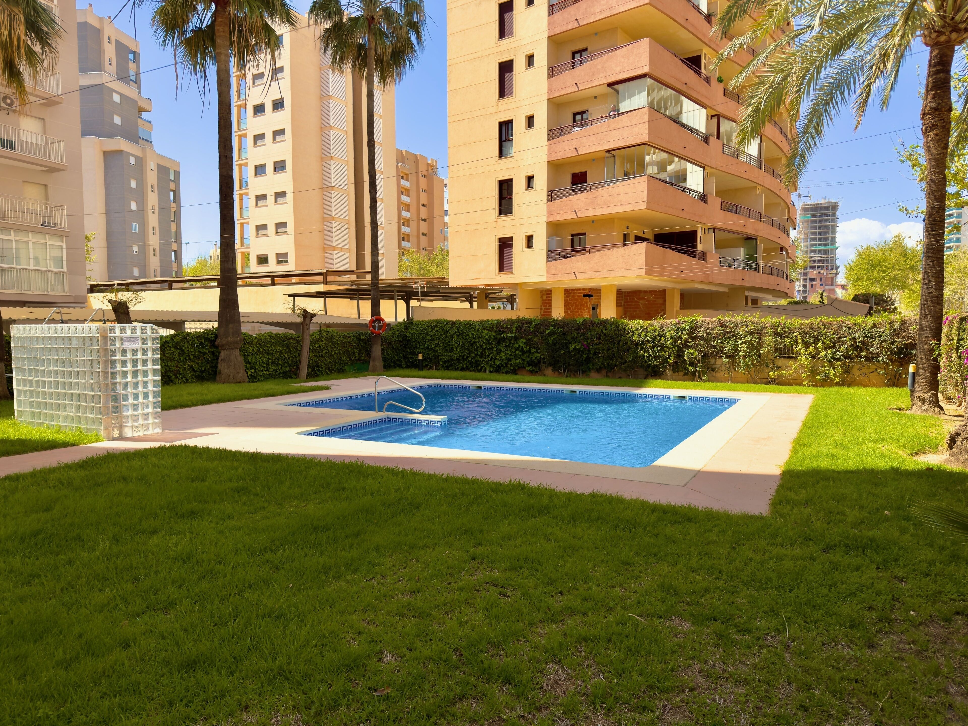 Un edificio residenziale con piscina, immerso nel verde e palme.