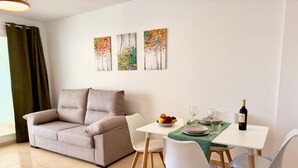 Un salon moderne avec un canapé beige, une table à manger avec des chaises et trois œuvres d’art accrochées au mur.