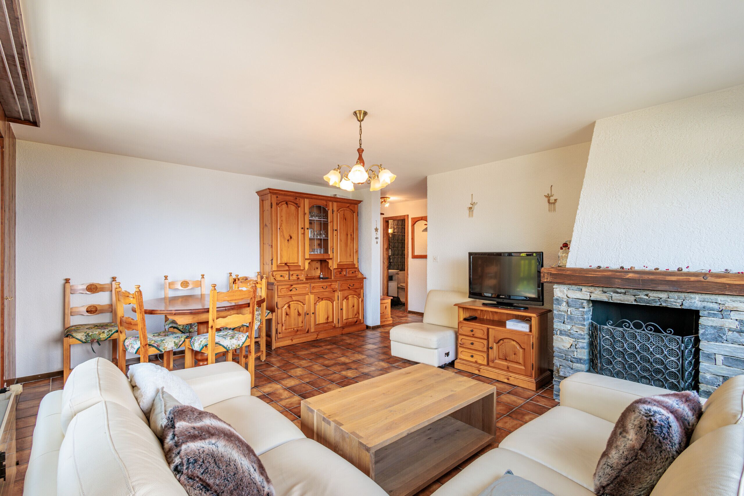A living room with a fireplace, wooden furniture, and a television.